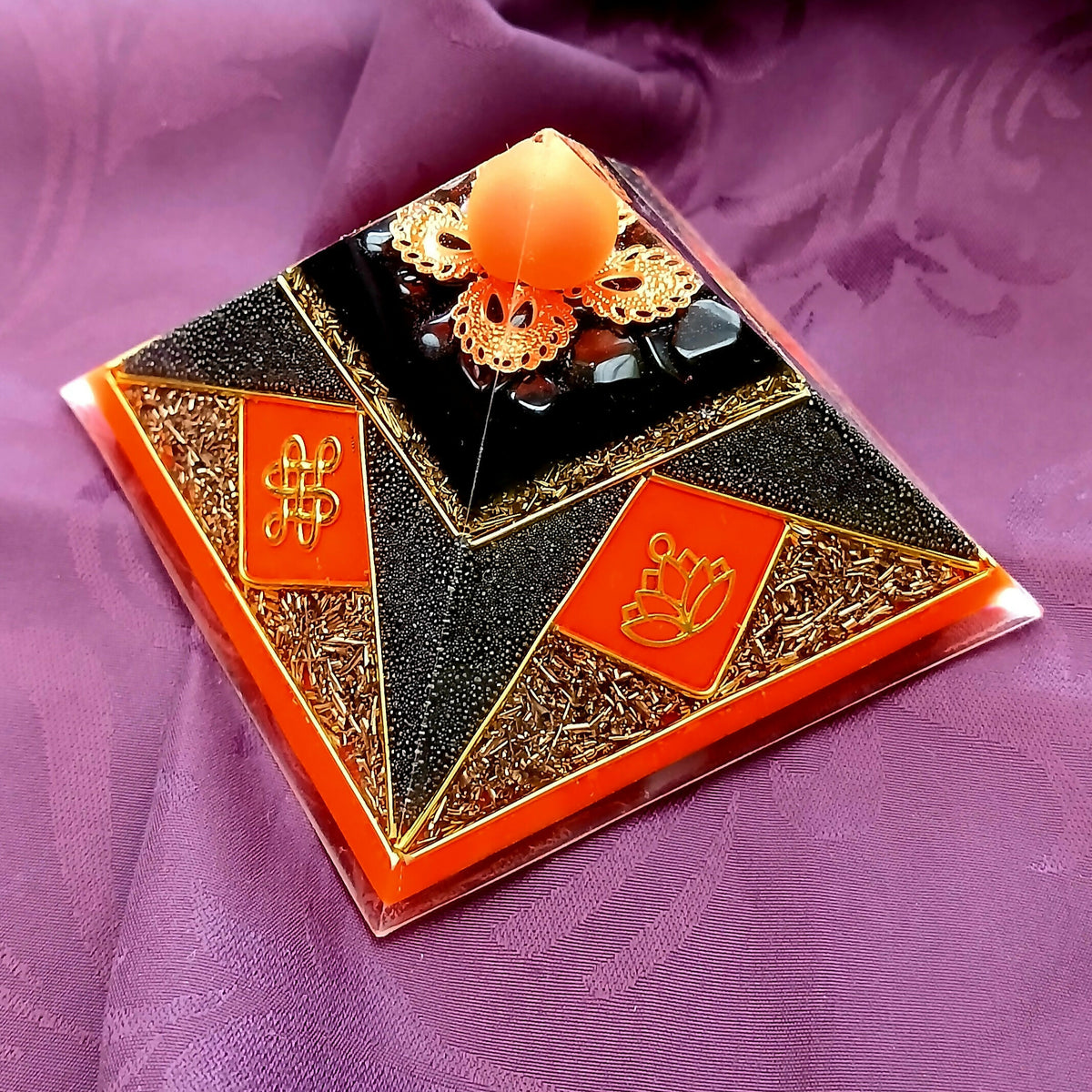 Small Neon Red Cheops Pyramid by Orgone Art Yvonne – low black pyramid with neon orange-red diamond panels bearing gold knot and lotus symbols, a copper filigree crown and orange sphere at the apex