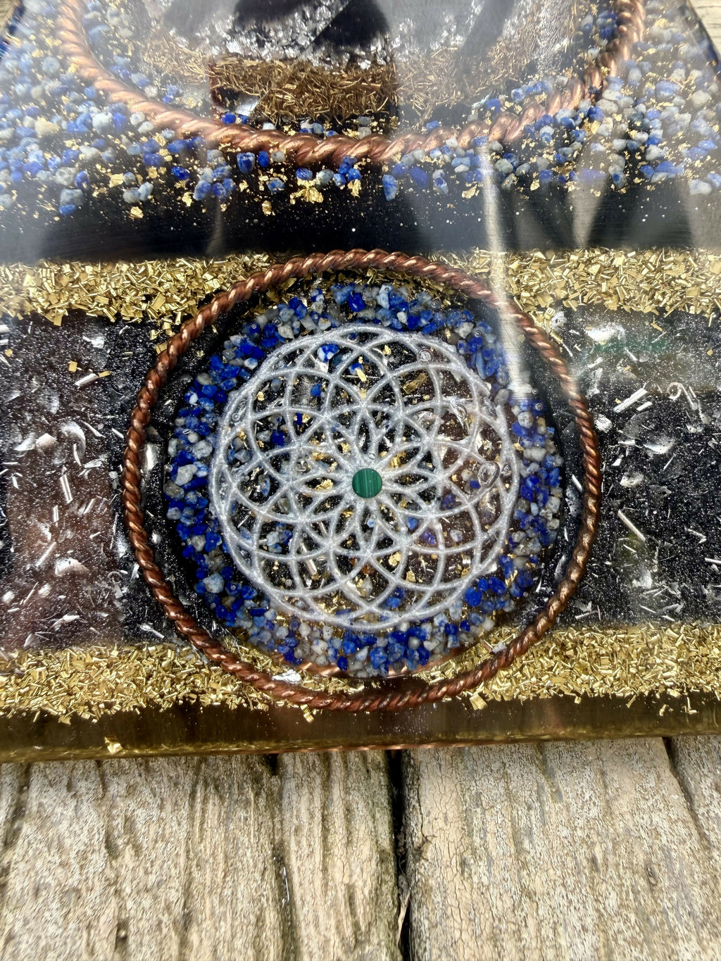 Close view of a side Torus symbol: silver-toned pattern with a green Malachite centre, ringed by Lapis Lazuli and twisted copper