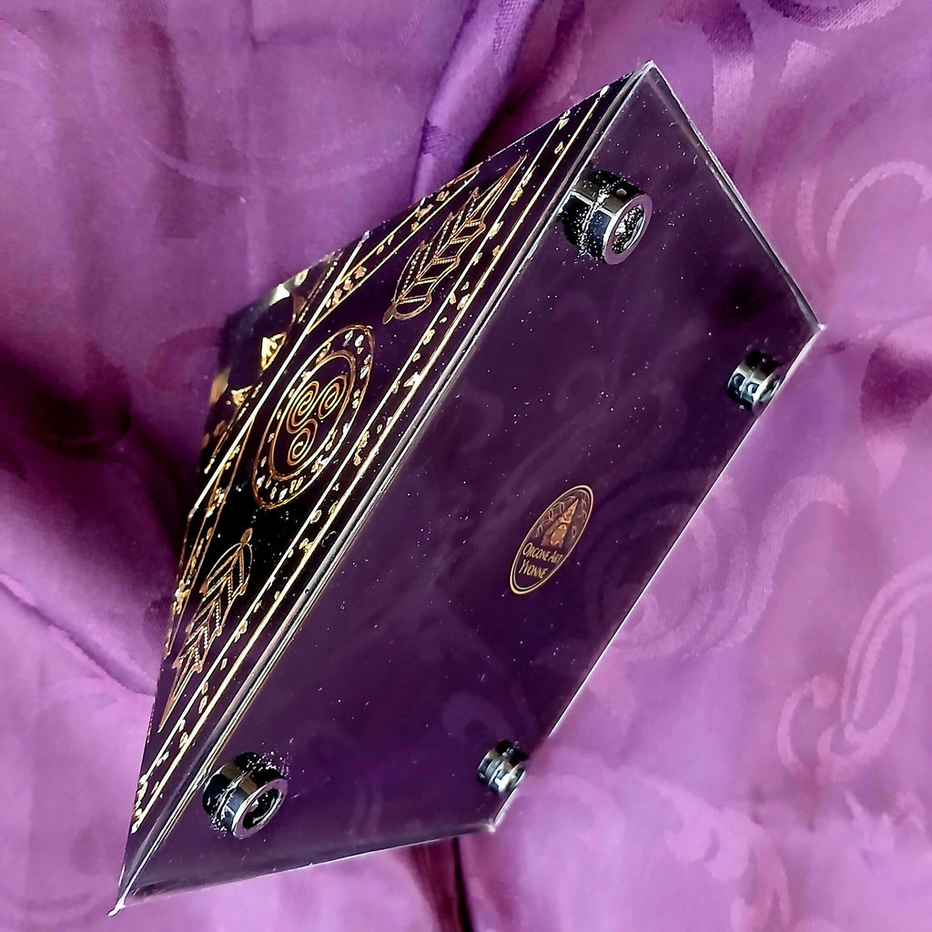 Pyramid tipped on its side showing the black base with round metal feet and a gold emblem