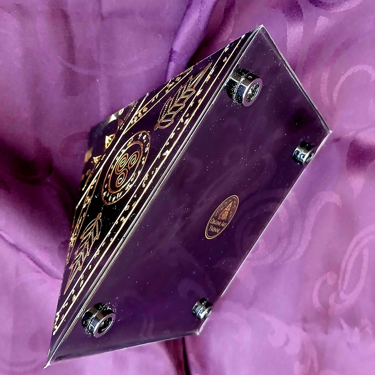 Pyramid tipped on its side showing the black base with round metal feet and a gold emblem