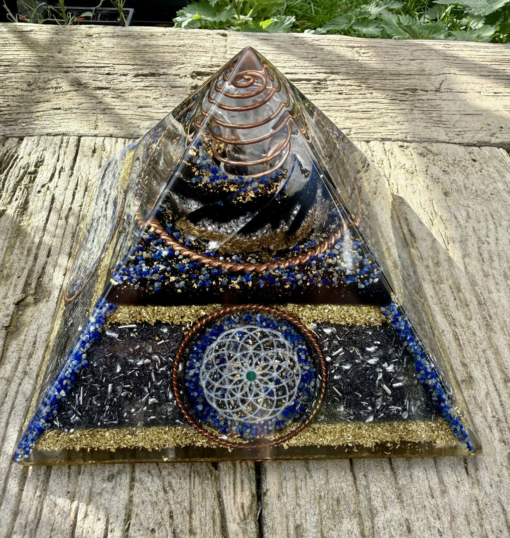 Front view of the pyramid outdoors, showing the dark lower layers, brass band and copper rings below the clear apex