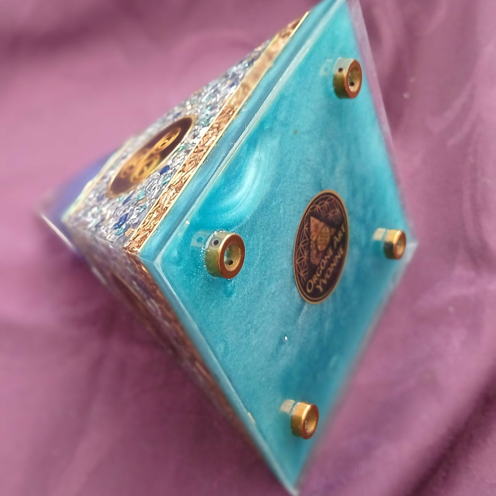Pyramid on its side showing the turquoise base with round gold feet and a central emblem