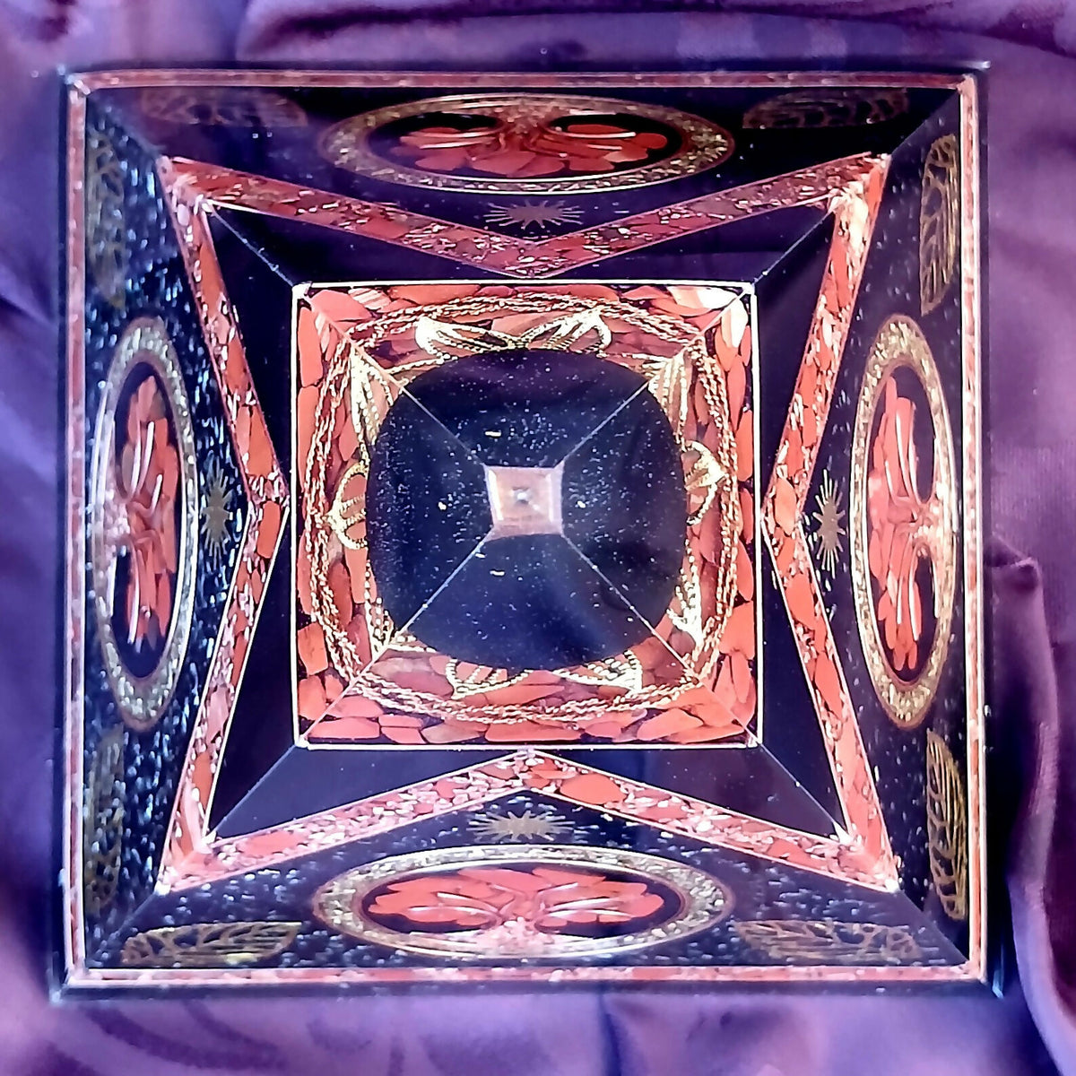 Top-down view of orgonite pyramid showing four Tree of Life panels around the clear apex.