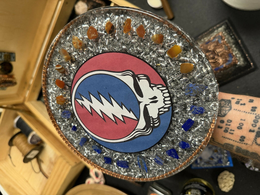 Closer view of the round plate showing the skull design and the ring of orange and blue stones