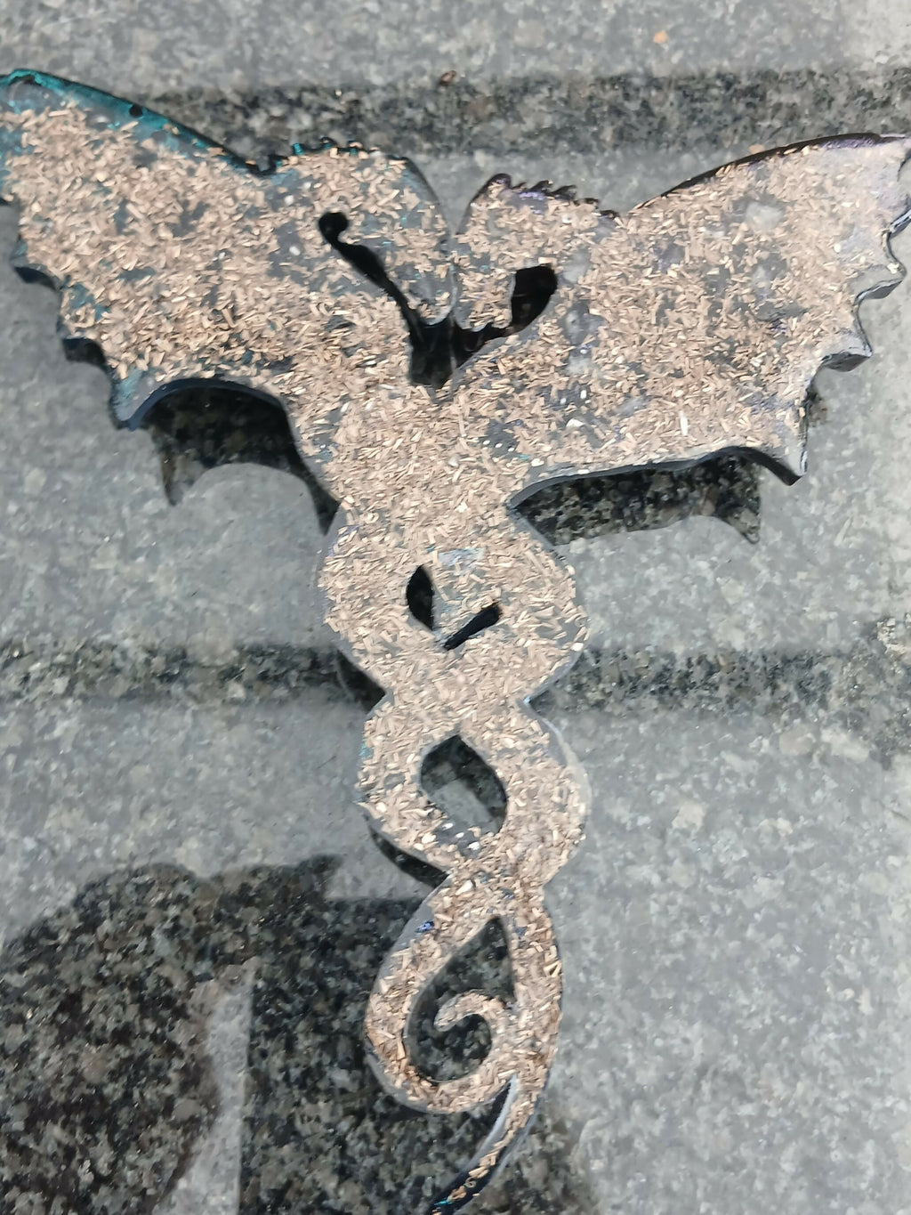 Back of a dragon wall piece showing the flat dark surface with gold-coloured metal flakes