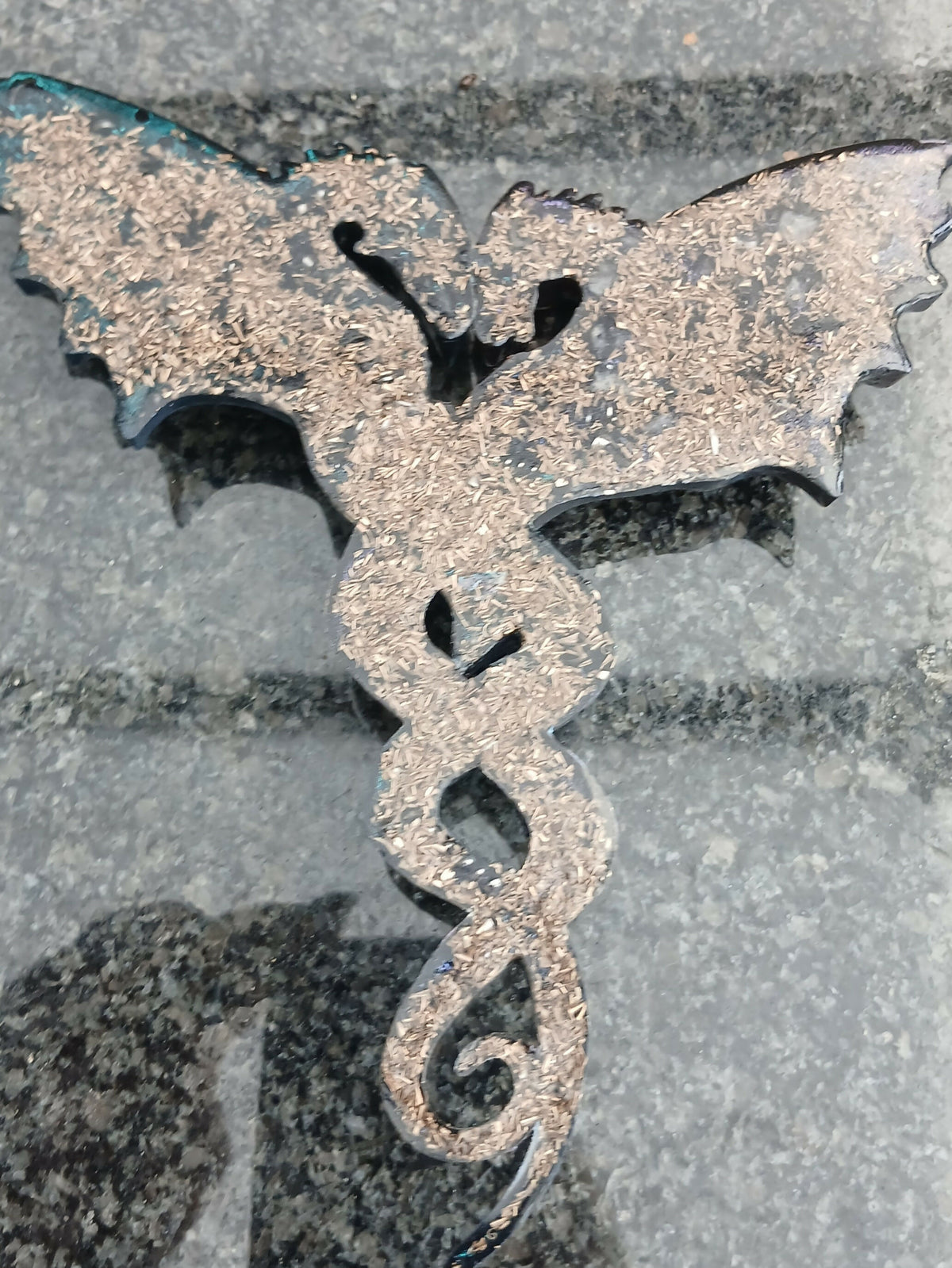 Back of a dragon wall piece showing the flat dark surface with gold-coloured metal flakes