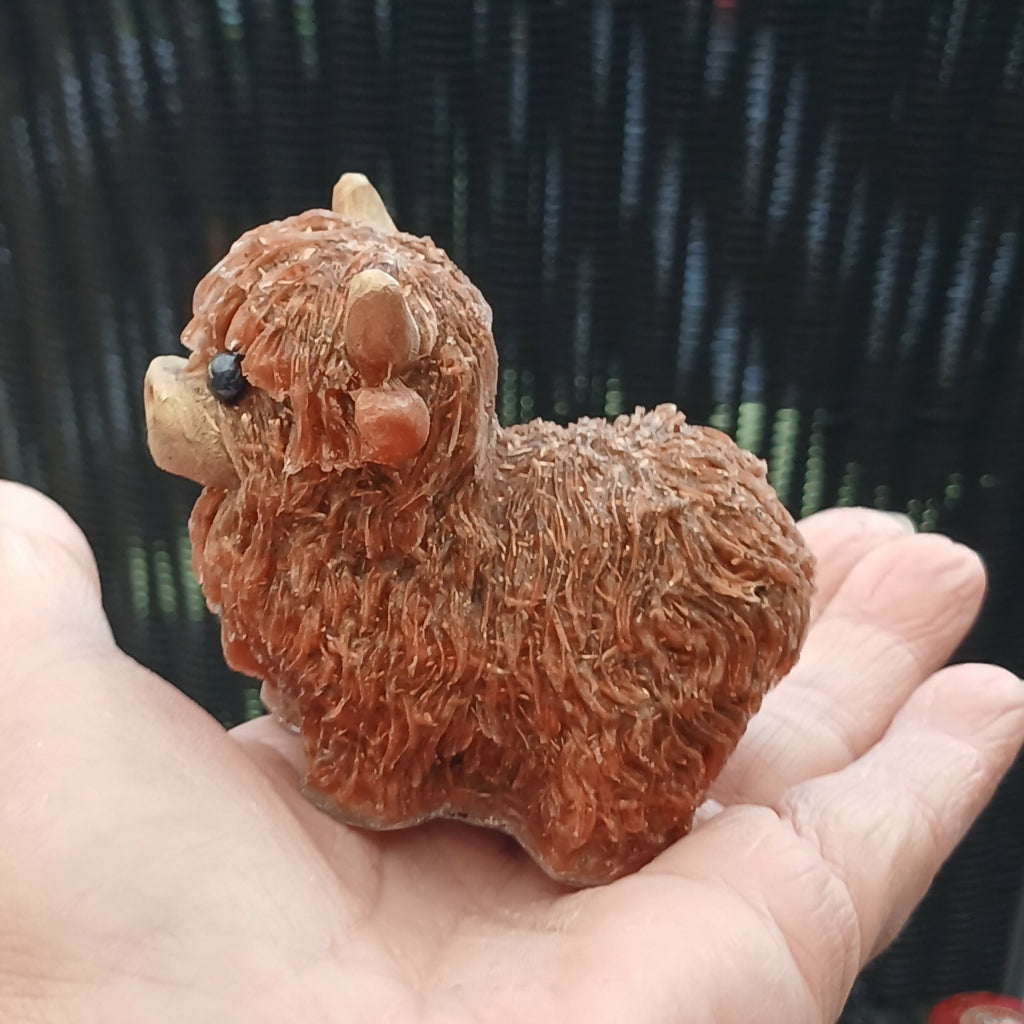 Brown Highlander Coo figure resting on an open hand, showing its small size and textured coat