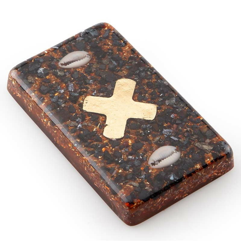 Rectangular brick with a gold cross in the centre and two small white cowrie shells set in brown chips