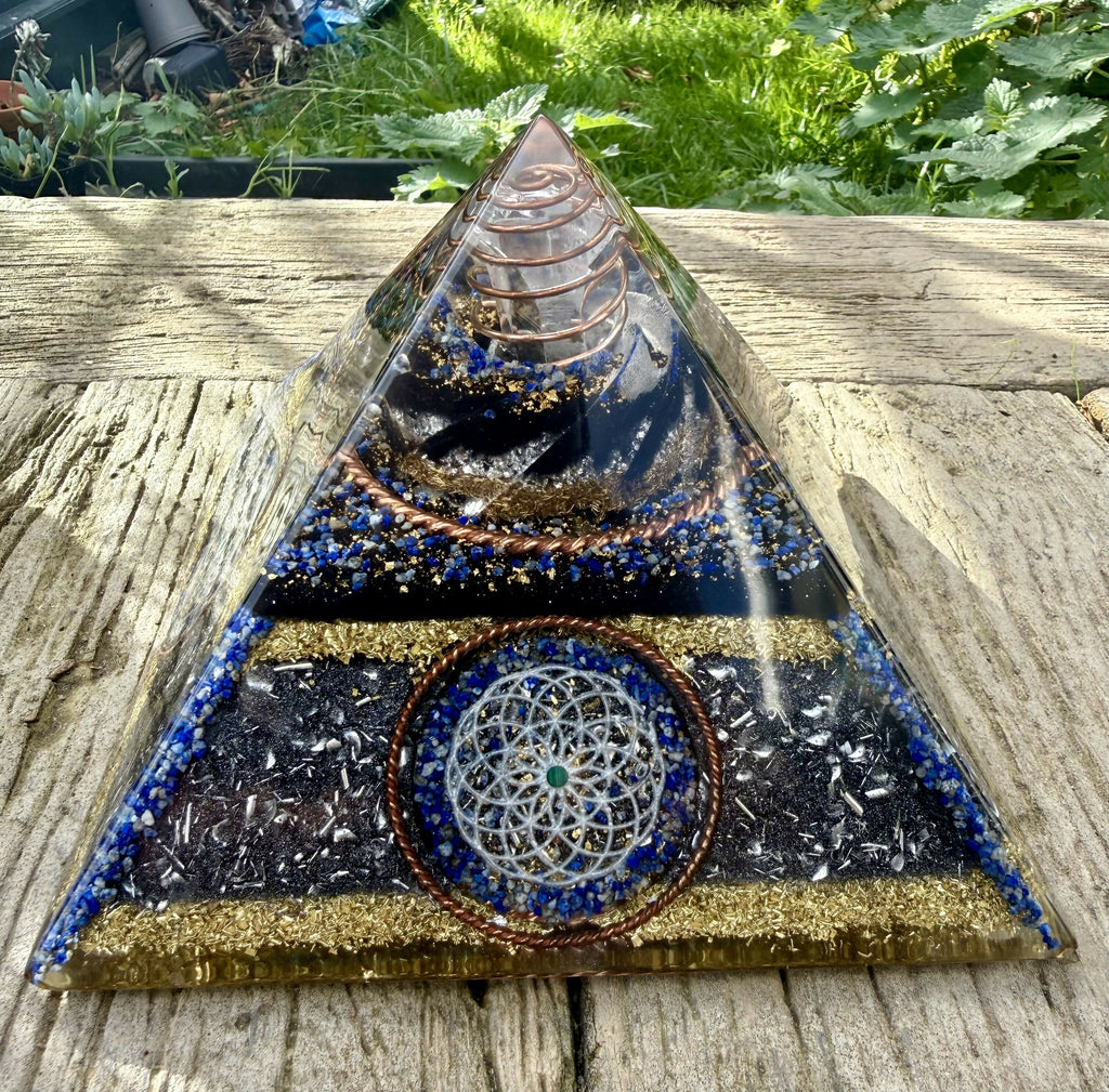 XL Torus & Lapis Orgonite Pyramid by Orgone Solutions – front view on a wooden table, with a silver Torus disc set in Lapis Lazuli, blue lapis bands and a copper coil in the clear apex