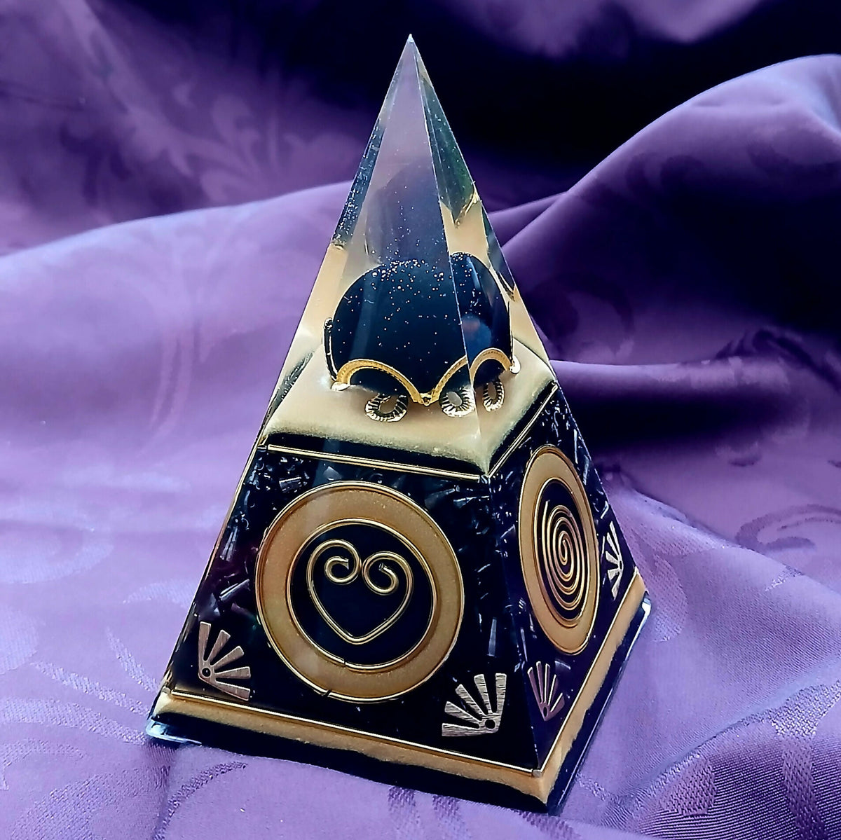 Front face showing a gold disc with a heart-shaped spiral below the dark heart in the tip