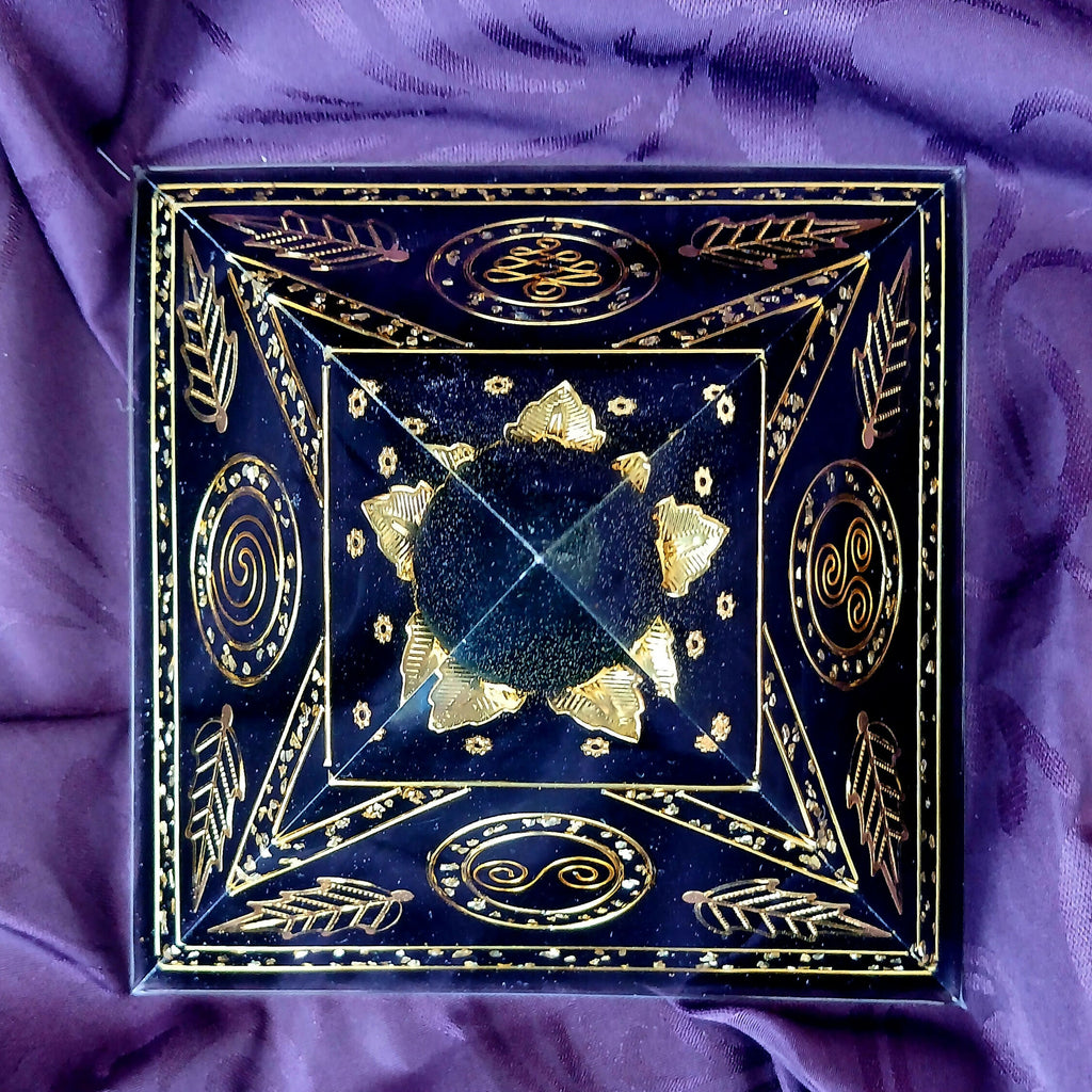 Top-down view of the pyramid with gold spirals and leaf motifs on each face and gold triangles around a clear apex