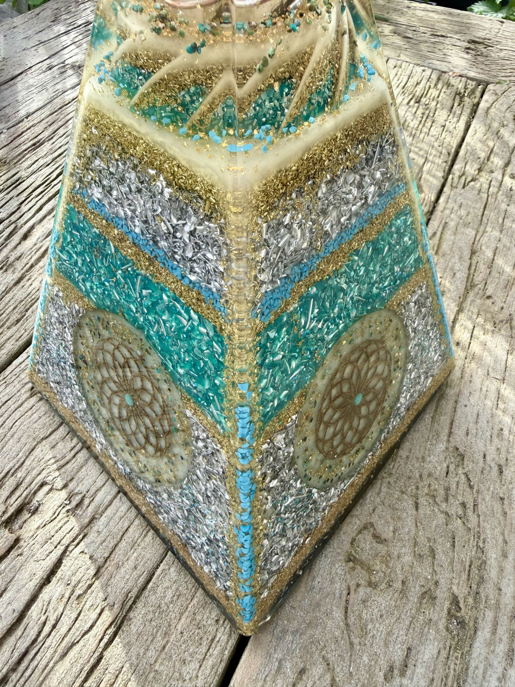 Corner view of two faces with turquoise, silver and gold bands and a gold Flower of Life disc on each side