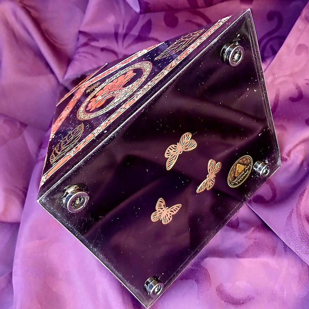 Underside of orgonite pyramid with butterfly decorations, four round feet and creator label.