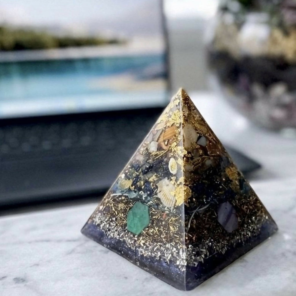 Pyramid on a marble desk in front of a laptop, side view of its dark blue base and shell layer