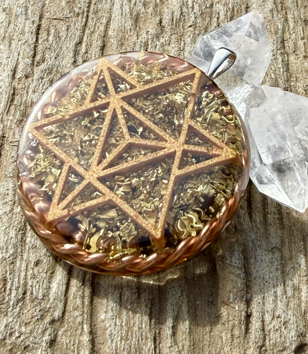 Pendant at an angle showing the star tetrahedron design, metal flakes and twisted copper rim beside clear quartz points