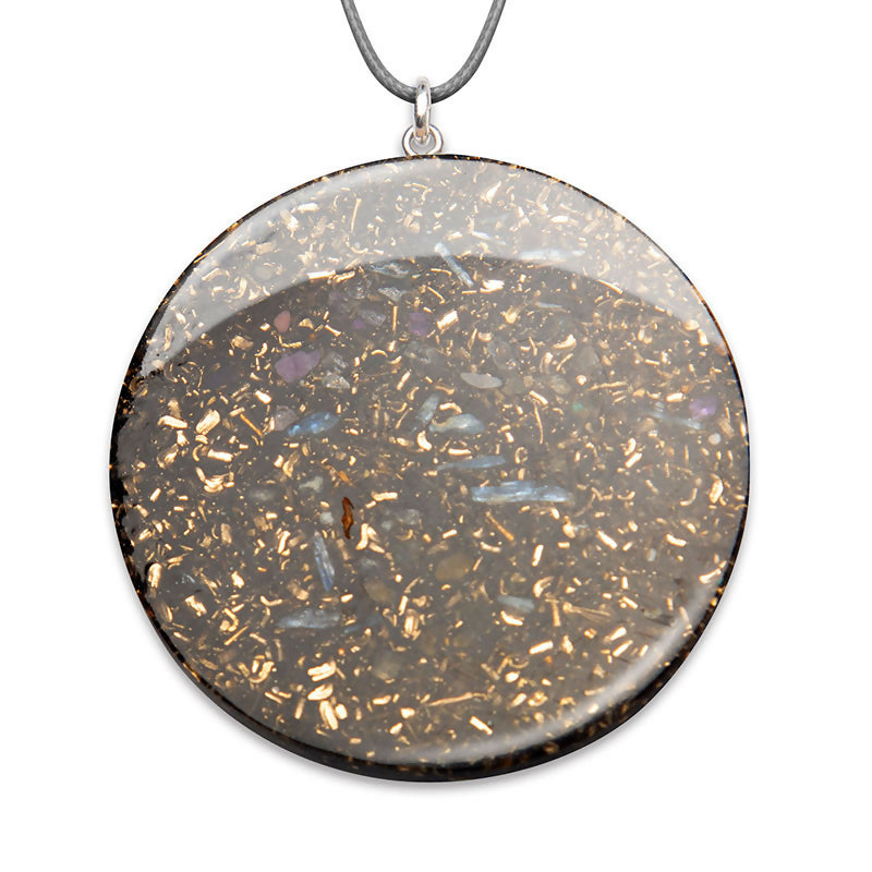 Round pendant with a dark grey back, metal flakes and a clear domed top, on a grey cord
