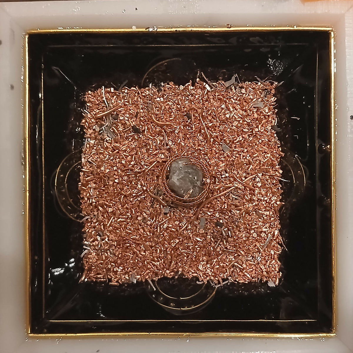 Work in progress: a dense layer of copper-coloured granules with a clear stone at the centre