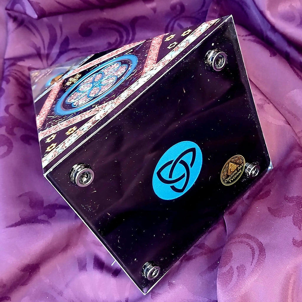 Underside of orgonite pyramid with blue triquetra symbol, four round feet and creator label.