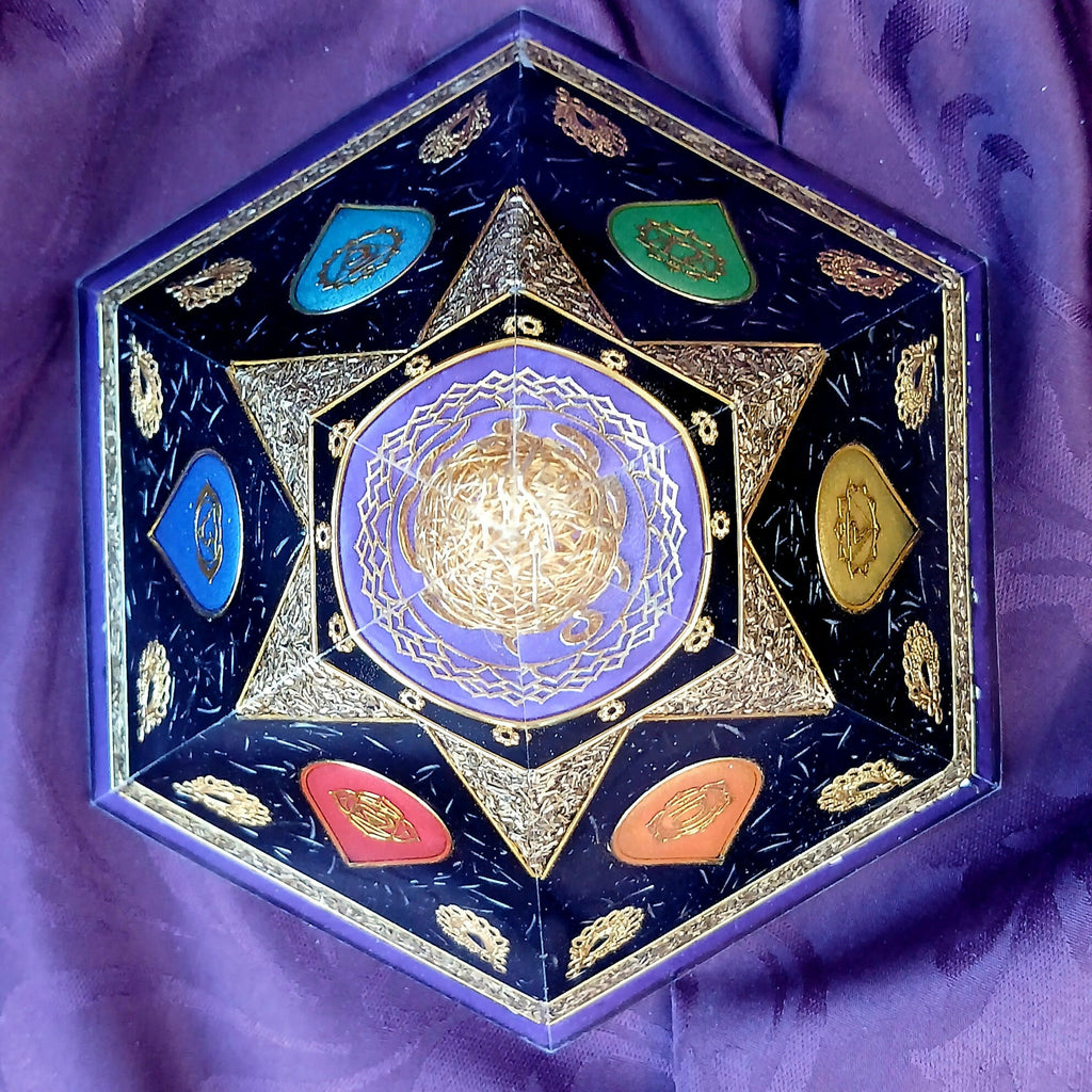 Top-down view of six-sided orgonite pyramid with six coloured chakra panels around a purple central design.