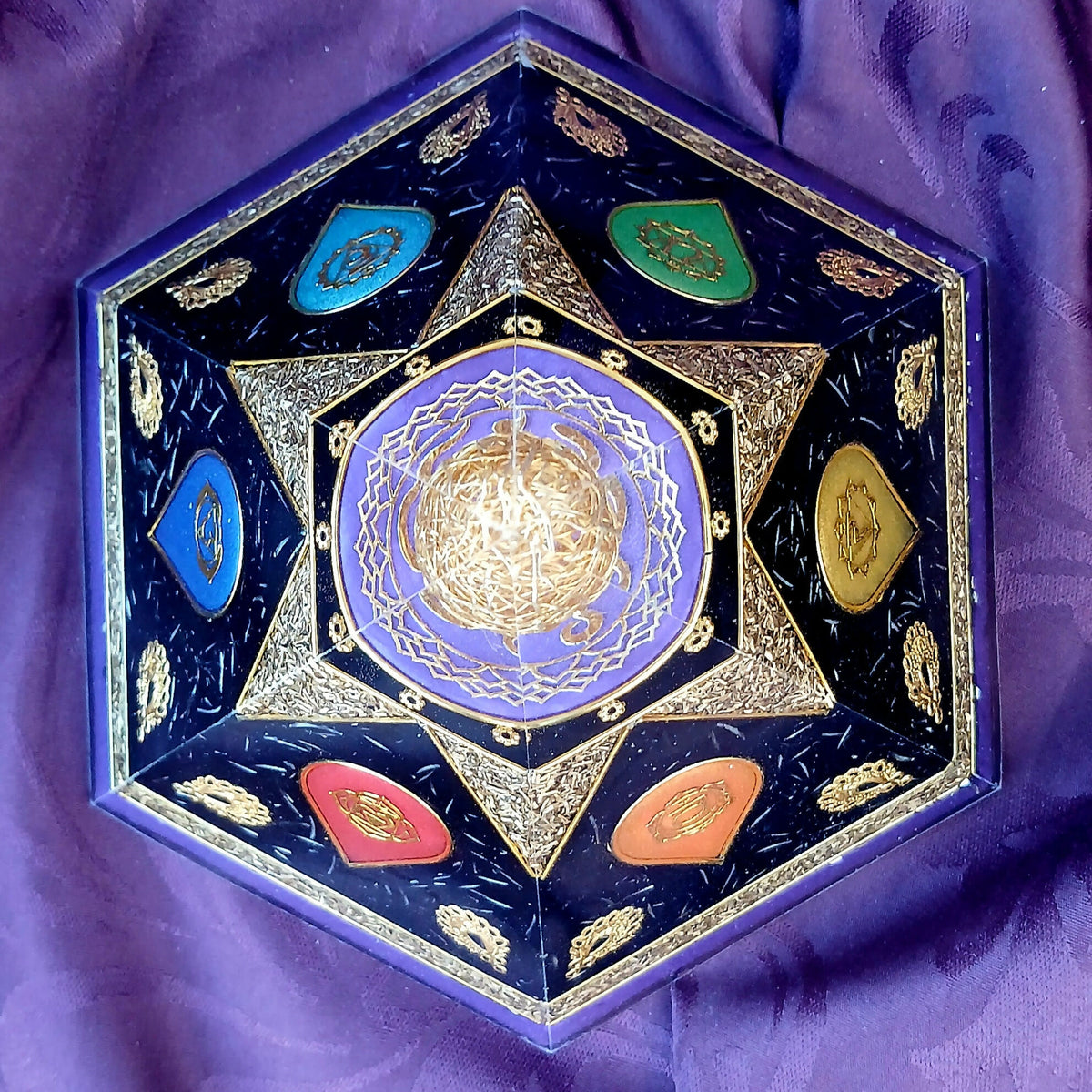 Top-down view of six-sided orgonite pyramid with six coloured chakra panels around a purple central design.