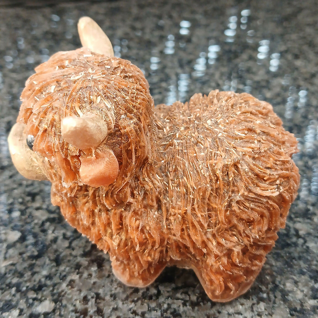 Side view of the brown Highlander Coo figure, showing its rounded body, short legs and textured shaggy coat