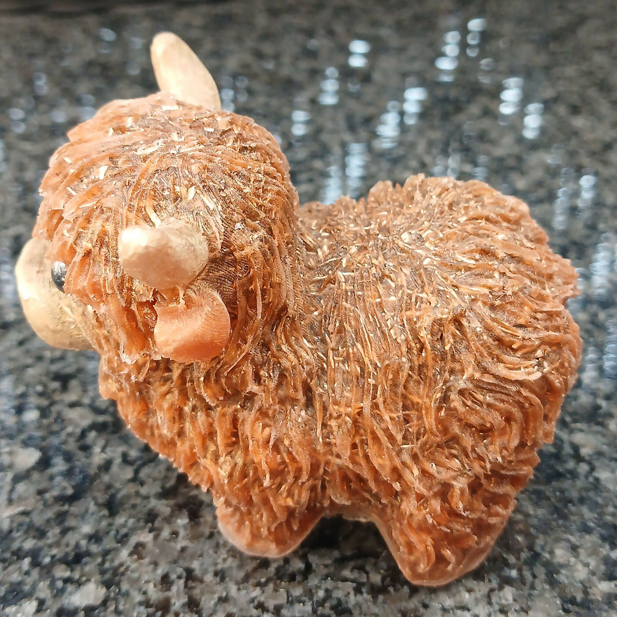 Side view of the brown Highlander Coo figure, showing its rounded body, short legs and textured shaggy coat