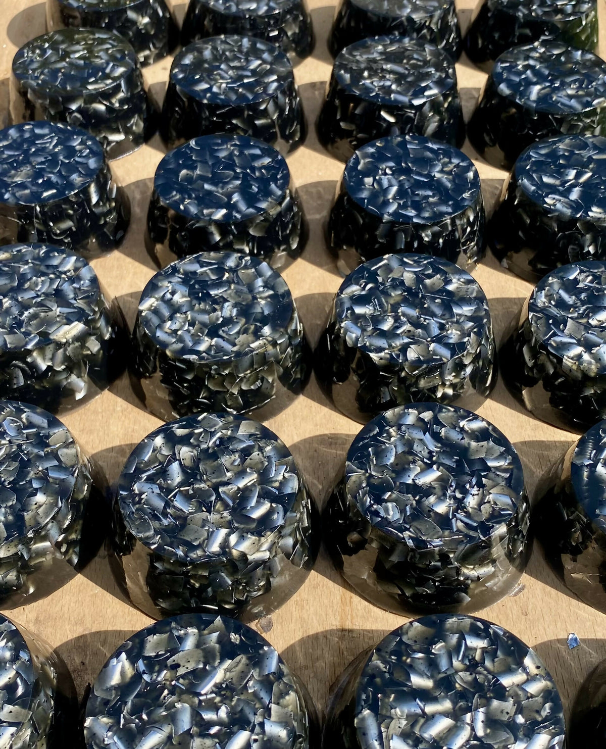 A larger batch of black shungite orgonite towerbusters in a tray, viewed from above