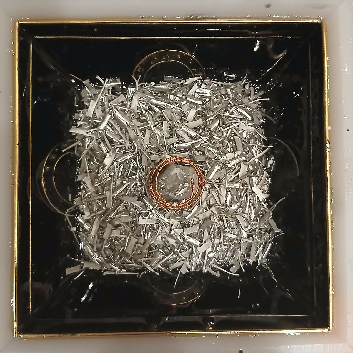 Work in progress: a layer of silver-coloured metal shavings around a copper coil in the mould