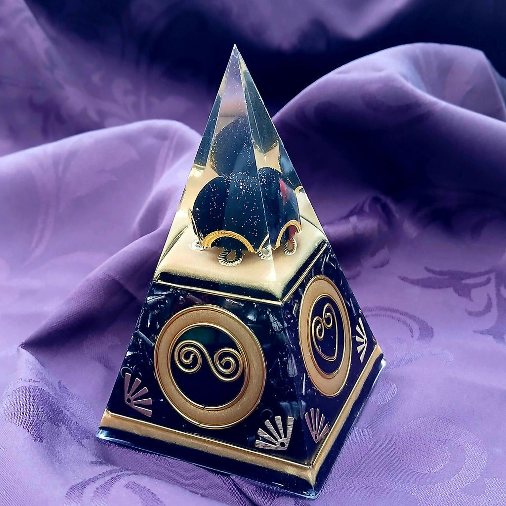 Small Nubian Pyramid Black & Gold by Orgone Art Yvonne – steep black pyramid with a dark glittery heart in the clear tip, gold spiral and heart discs and small gold fan motifs