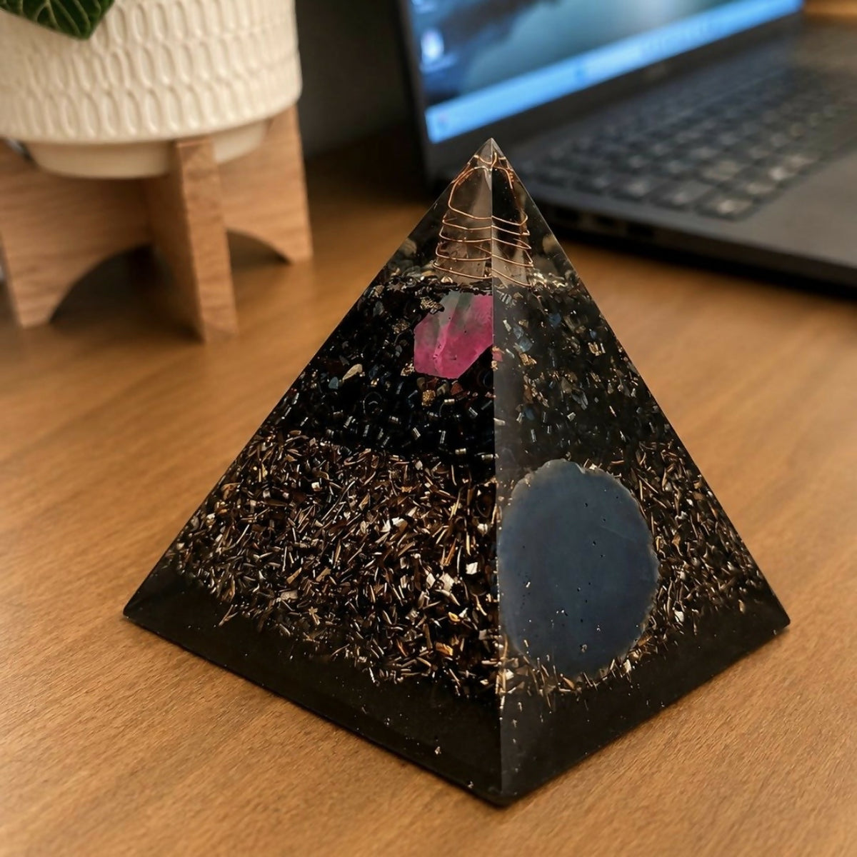 Pyramid on a wooden desk near a laptop, side view of the shavings layer and blue slice