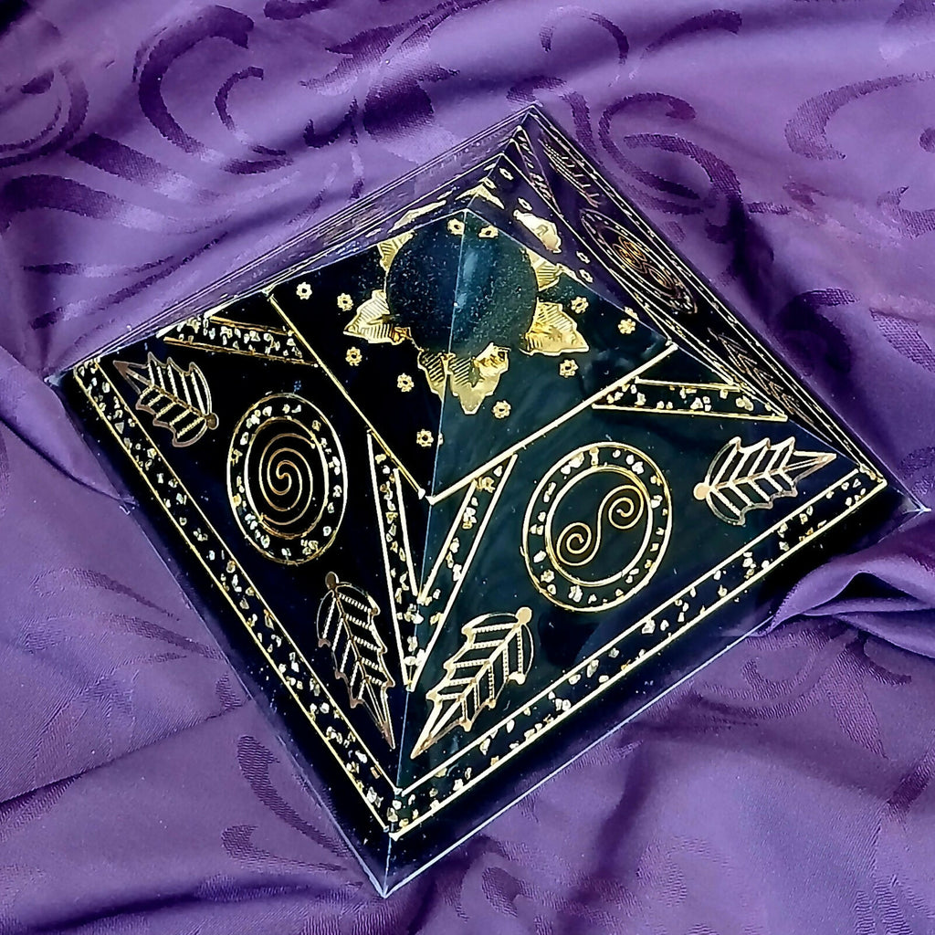 Angled view of the black pyramid showing gold spiral discs, leaf patterns and gold flakes around the apex