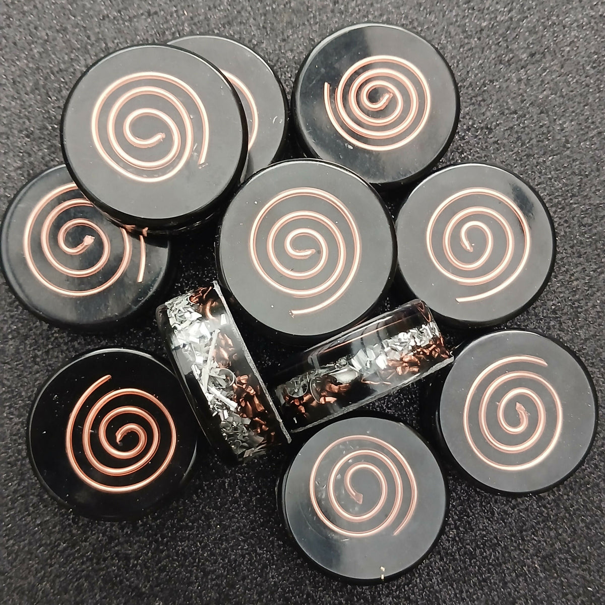 Close group of round black pocket discs, each with a raised copper spiral on top