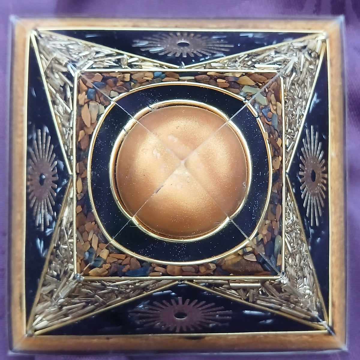 Top-down view of the apex sphere framed by brown chips, black panels and gold sunburst designs