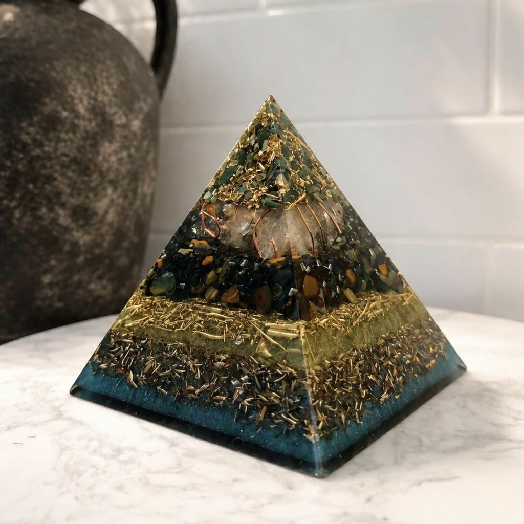 Front view of the Bloodstone and Kambaba Jasper pyramid by Piezo & Co on white marble beside a dark stone jug