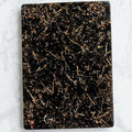 Grounding Orgonite Charging Plate by Piezo & Co – rectangular black plate with gold-coloured metal shavings, top view on white marble