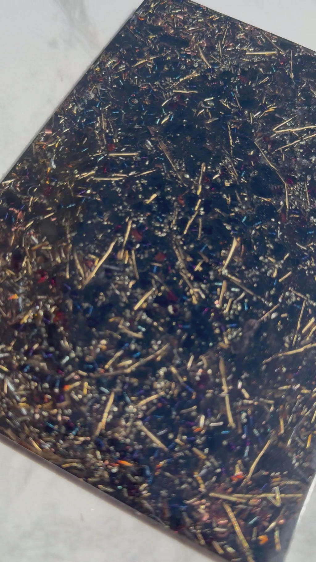 Short video of the Grounding plate on white marble, showing metal shavings and small red stones in dark resin