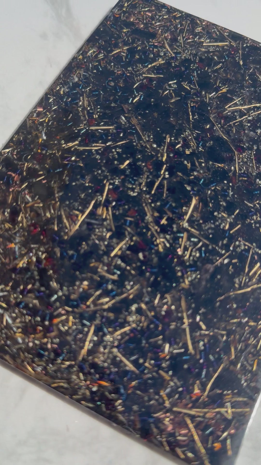 Short video of the Grounding plate on white marble, showing metal shavings and small red stones in dark resin