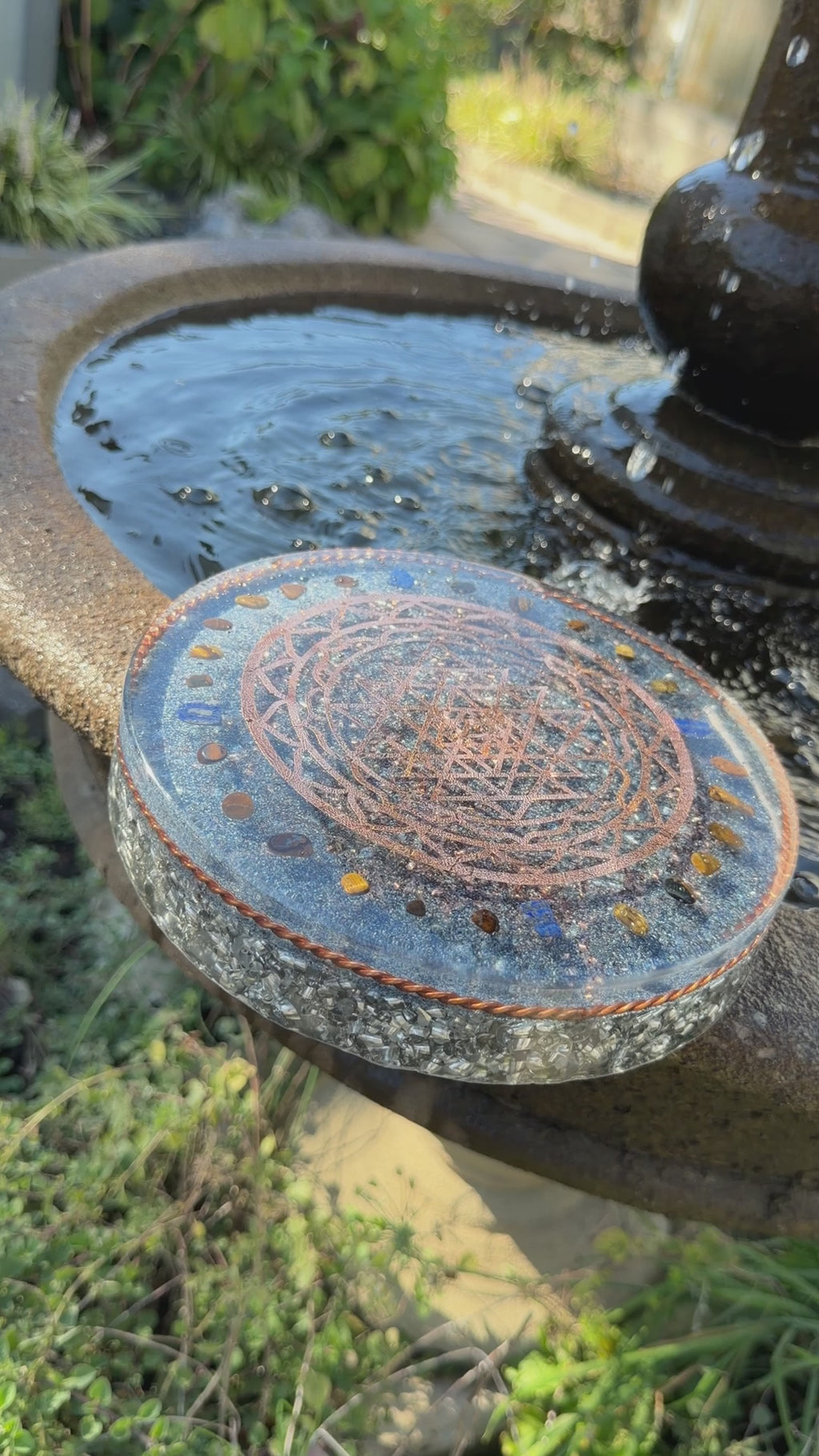 Short video of the Sri Yantra Charging Plate resting on the edge of a garden fountain
