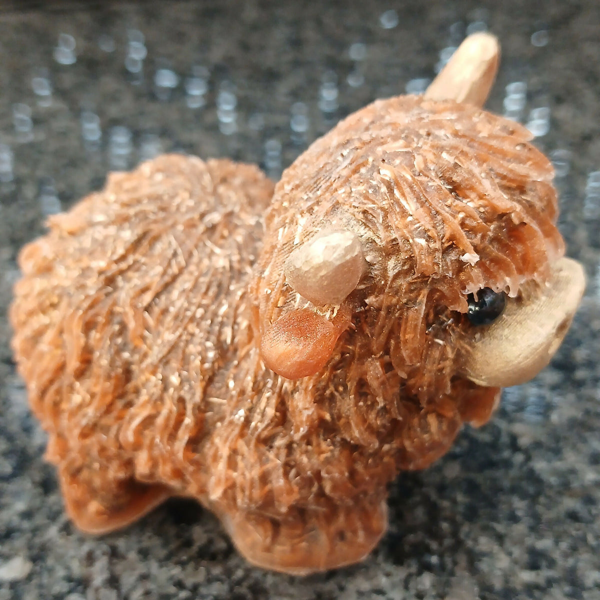 Highlander Coo figure viewed from above at an angle, showing its textured brown back, shaggy head and pale horns