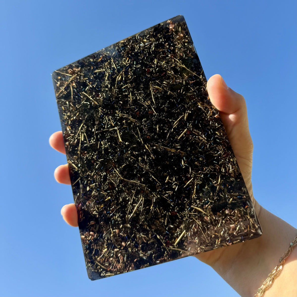 The plate held up against a blue sky, showing metal shavings set in dark resin