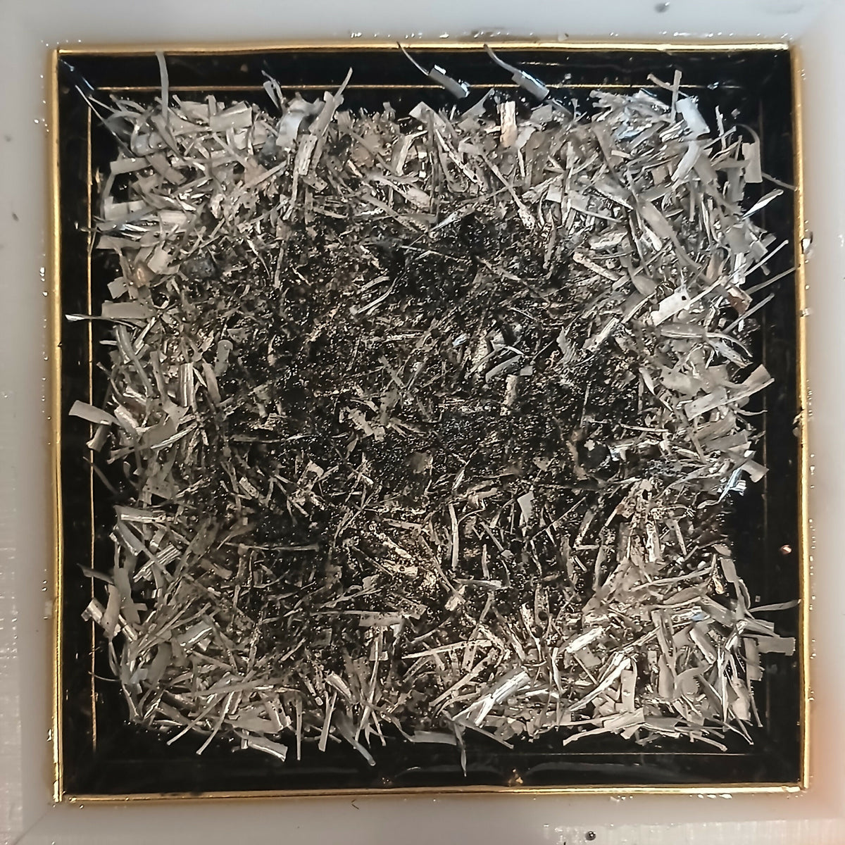 Work in progress: silver-coloured metal shavings over a darker layer filling the mould