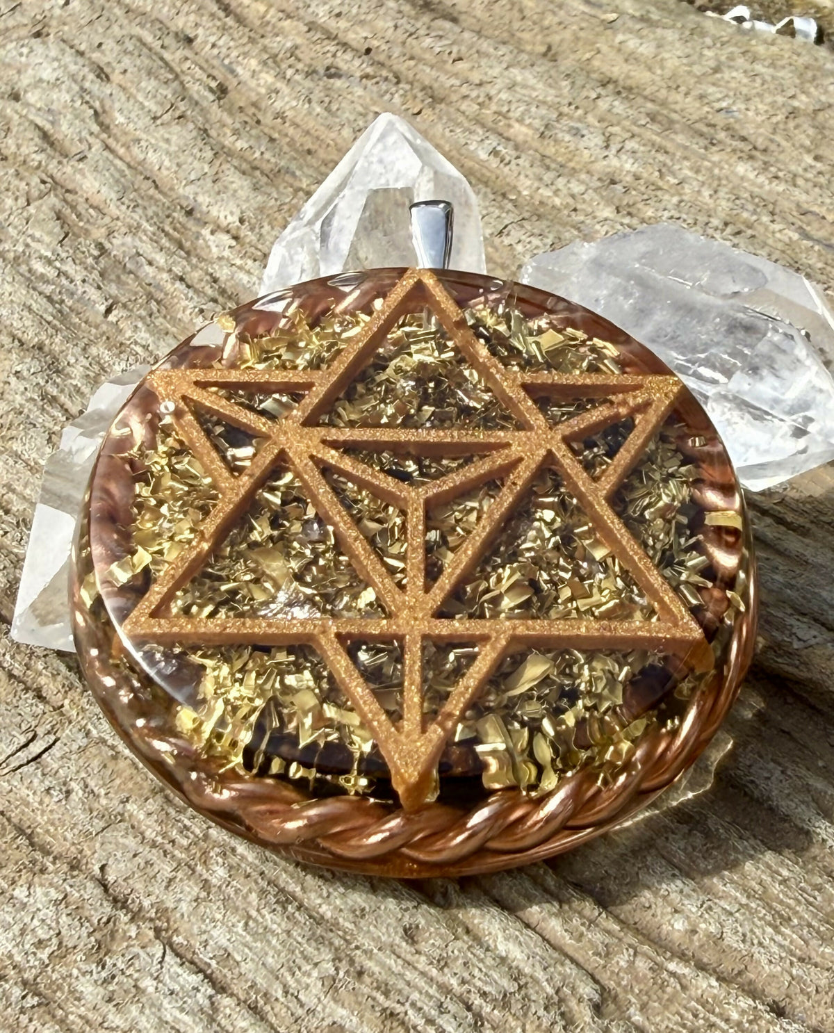 Front view of the copper-coloured star tetrahedron design over gold-coloured flakes and dark stones