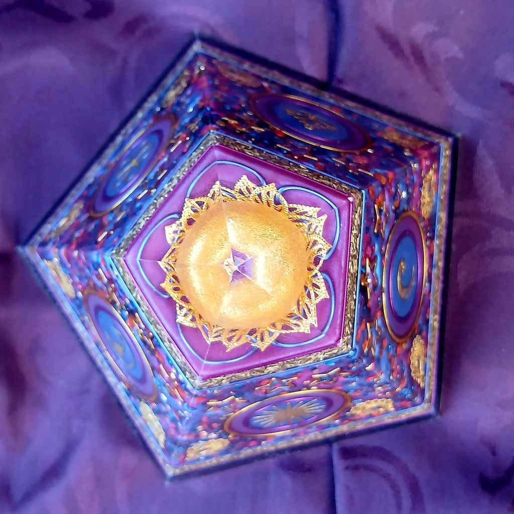 Top-down view of five-sided orgonite pyramid with a golden circular decoration around the clear apex.