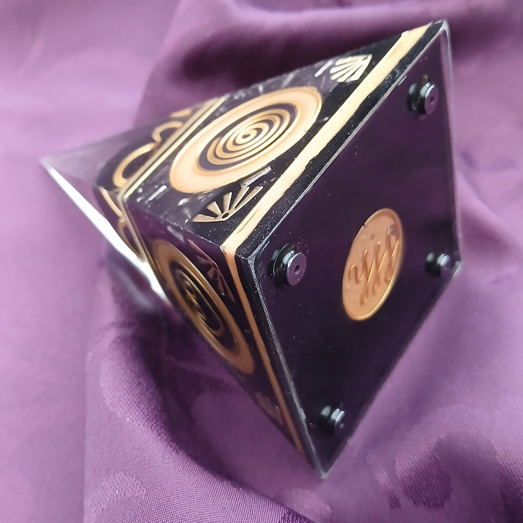Pyramid on its side showing the black base with metal feet and a round copper-coloured label
