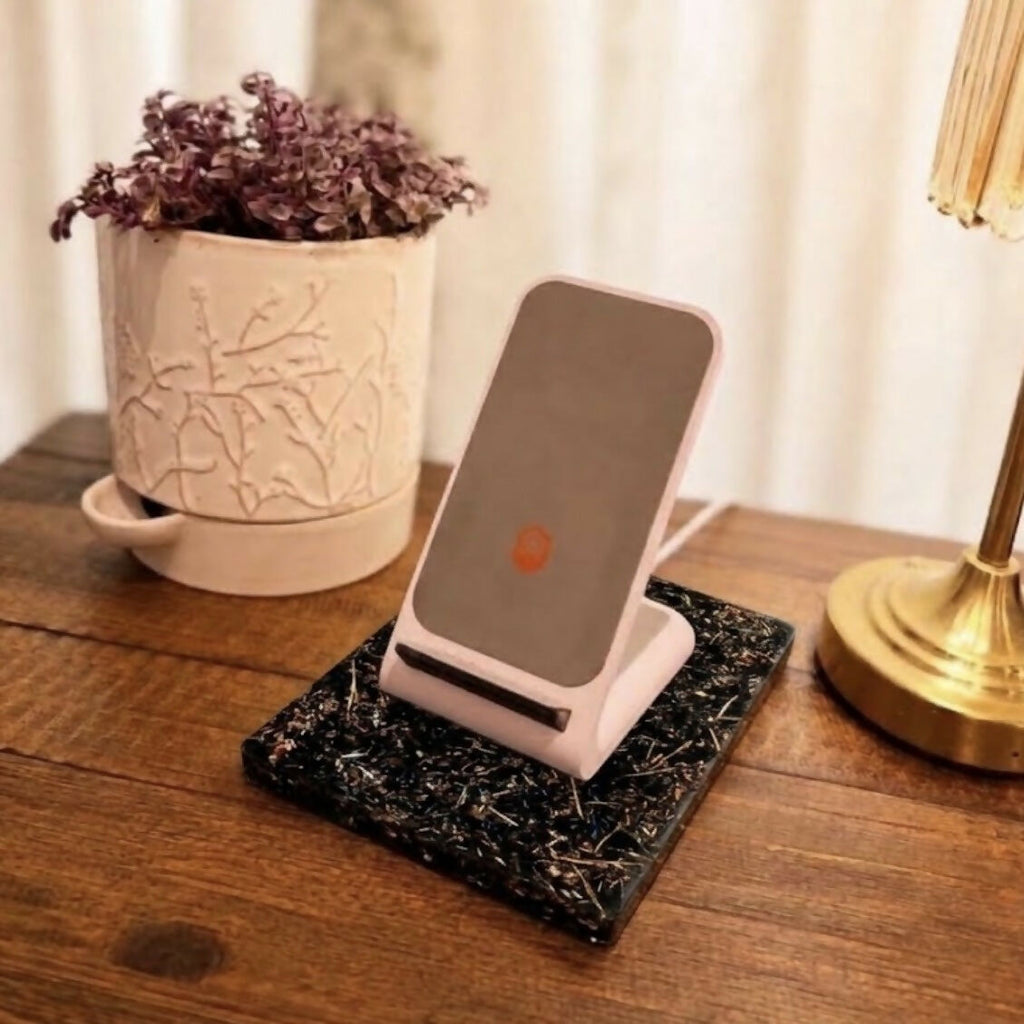 The plate on a wooden table with a pink phone stand resting on it, beside a potted plant and a brass lamp