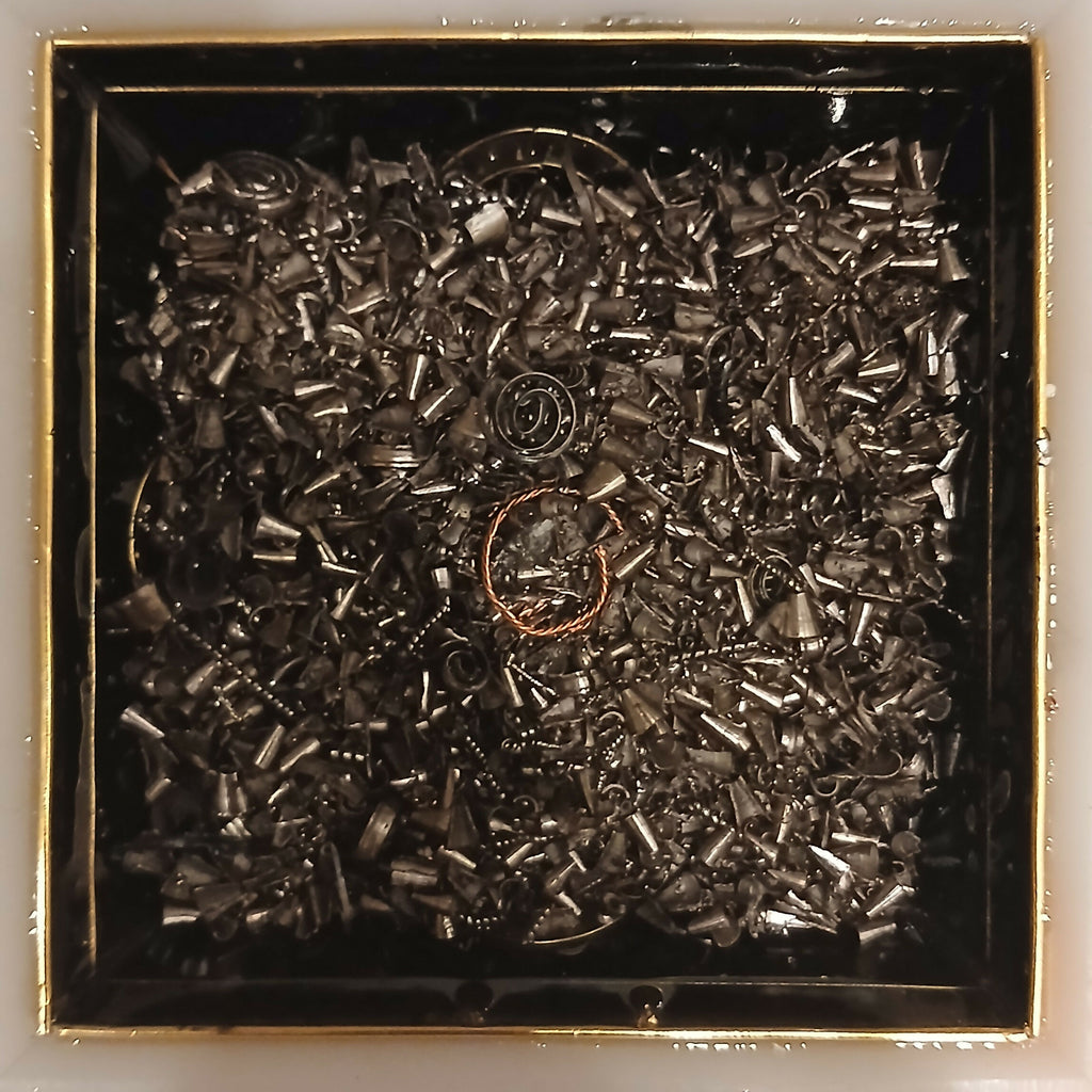 Work in progress: dark metal pieces filling the mould with a copper coil visible in the middle