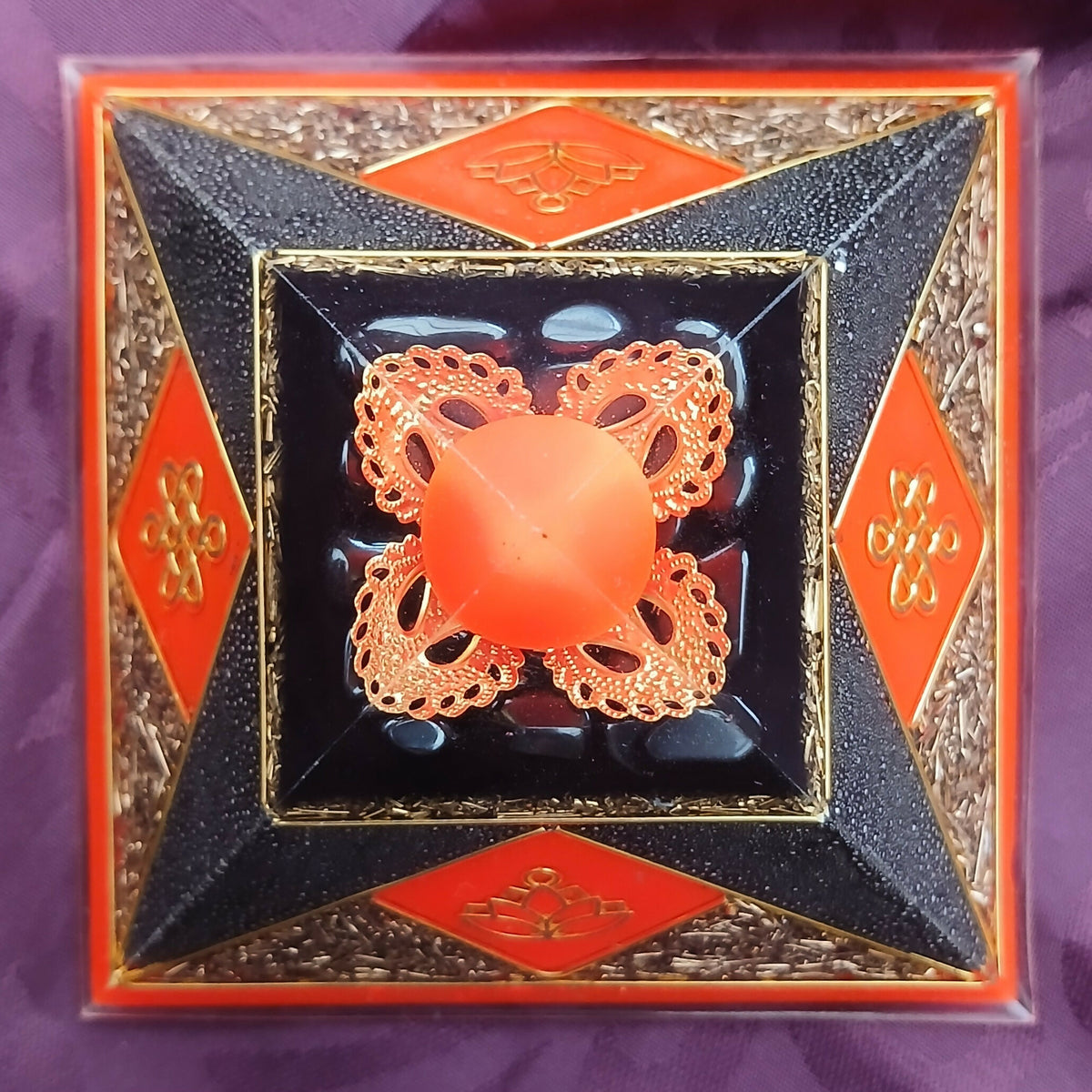 Top-down view of the orange apex sphere in copper filigree, framed by black faces and orange diamonds