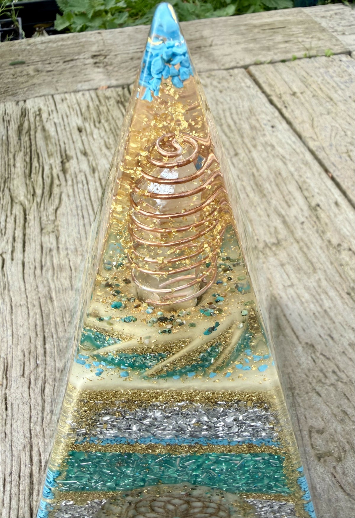 Close view of the upper section showing a copper coil around a clear point, turquoise chips at the tip and gold glitter bands