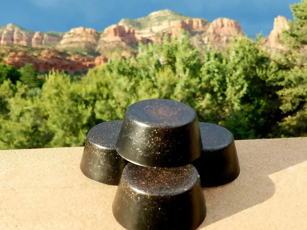 Four black tower busters stacked and grouped outdoors with red rocks and trees behind